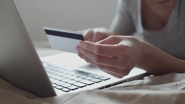 Girl in bed shopping online with credit card