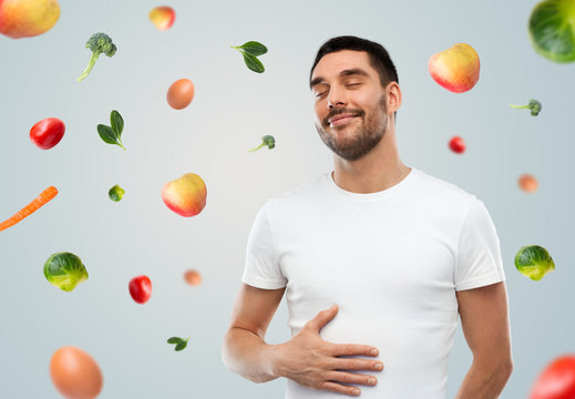 Happy Full Man Touching Tummy Over Falling Fruits