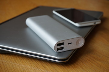 Mobile office with aluminum laptop, cell phone and power source (power bank) on the wooden table 