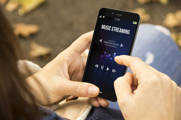 woman listening music with phone in the park