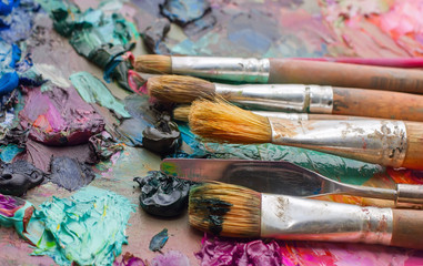 Used brushes on an artist's palette of colorful oil paint for dr