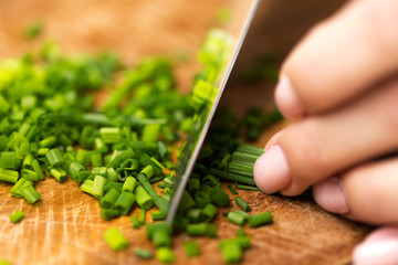close up of woman chopping green onion with knife