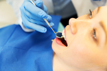 close up of dentist examining female patient teeth
