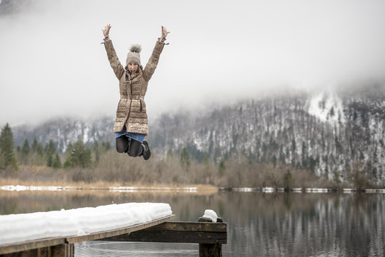 Woman in mid-air jumping near lake