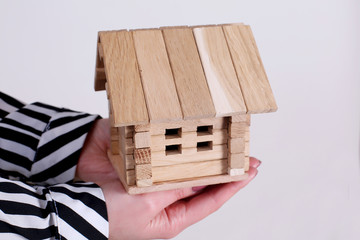 holding house representing home ownership and the Real Estate business