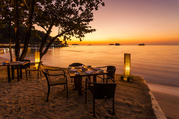 Naklejka premium Romantic sunset on the shore of a tropical island. Cafe on the b