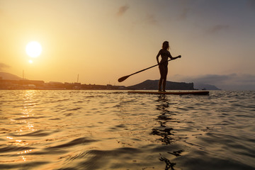 Silhouette of a beautiful woman on Stand Up Paddle Board. SUP.
