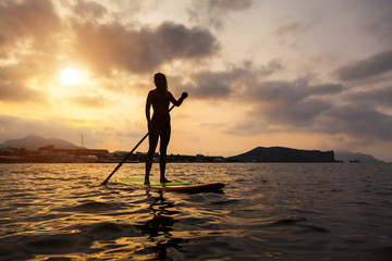Silhouette of a beautiful woman on Stand Up Paddle Board. SUP.