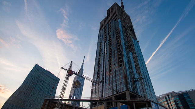 Sunset timelapse of skyscrapper construction works, pan