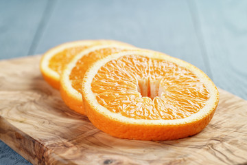 slices of ripe orange on olive cutting board, shallow focus