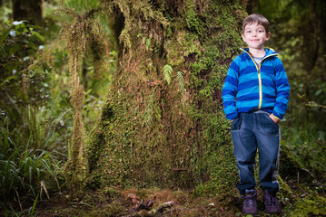 Young boy tourist posing in front of rain forest vegetation in New Zealand