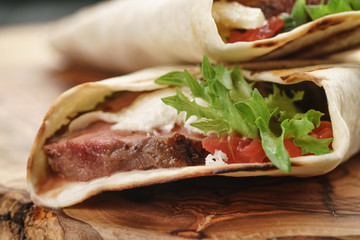 fresh homemade burritos with beef on olive cutting board shallow dof