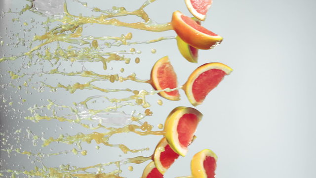 grapefruit slices fly with grapefruit juice, white background, slow motion