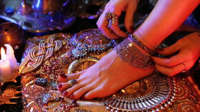 Indian Wedding Preparation. Luxury Oriental Fashion Accessories: Female foot and Hands, Beautiful National Indian Bridal Golden Jewellery. Eastern Traditional Sari clothes. Color lenses, Candlelight.