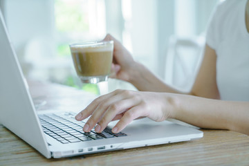 Closeup of business woman hand typing on laptop keyboard and cof