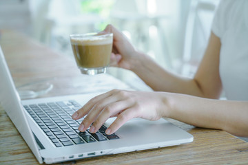 Closeup of business woman hand typing on laptop keyboard and cof