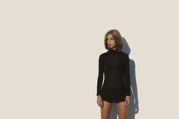 Girl in black sweater in the afternoon sun up against a white wall