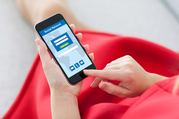 woman in red holding phone with social network on screen