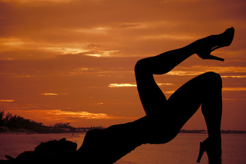 silhouette of woman by water in sunset lay on back leg up