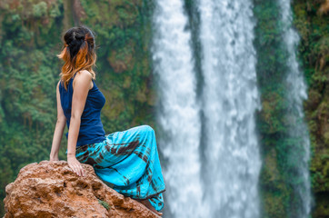 Girl on rock looking at waterfall background