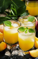 Cool summer peach juice with crushed ice, fresh peaches with lea