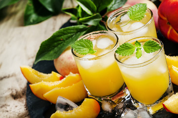 Cool summer peach juice with crushed ice, fresh peaches with lea