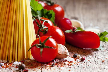 Italian dry pasta spaghetti with tomatoes and fresh herbs on a d