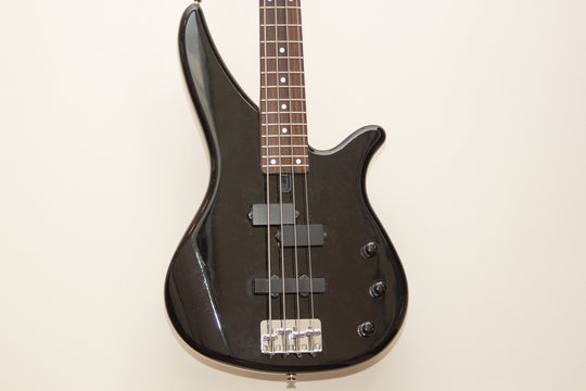 black bass electric guitar hanging on the wall
