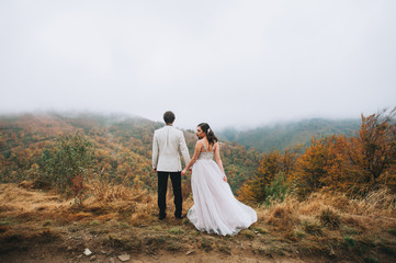 happy newly married couple posing in the mountains