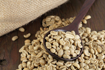 Coffee beans / Raw coffee beans in wooden spoon on wooden floor.