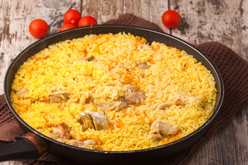 chicken pilaf in a frying pan on wood table