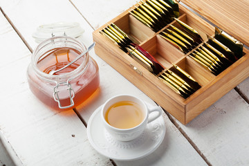 box with tea bag on wooden table, tea cup, honey