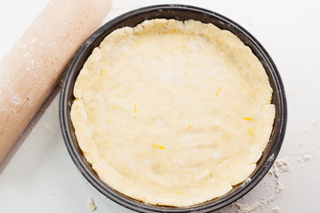 Block of freshly made pastry rolled out on a floured work surface with a wooden rolling pin