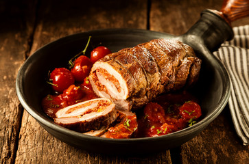 Stuffed pork roast and tomatoes in pan
