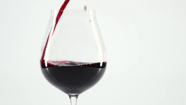 Splash of wine in the cup filling, white, slowmotion, close up