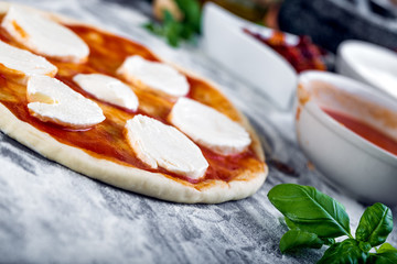 Prepering margherita pizza with mozzarella for baking