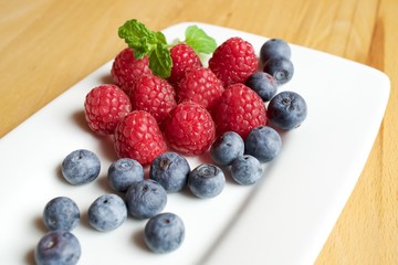 Himbeeren und Blaubeeren auf einer weißen Platte 