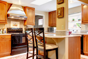 Kitchen with small island and stainless steal stove fan.