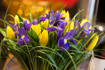 Bouquet of violet irises and yellow tulips in decorative paper w
