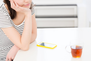 部屋でスマホを見る考える女性　手元