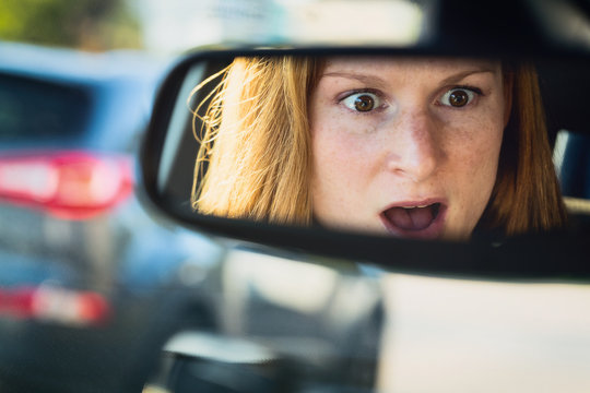 Scared Or Shocked Female Driver In A Car - Reflection In The Rear View Mirror.