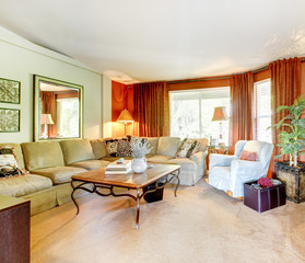 Living room with sectional couch, orange drapes, and wood coffee