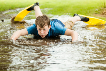 Teenager trying to swim in large puddle