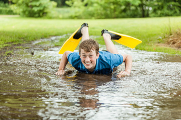Happy teen trying to swim in muddy puddle