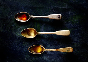red, olive, vegetable oil in a vintage spoon on a black background