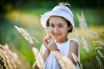 Beautiful toddler girl with long blond hair travels in colorful yellow field