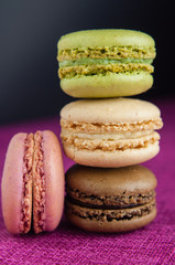 Stack of macaroons on pink jute tablecloth black background closeup