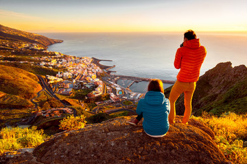 Young couple in colorful jackets enjoying landscape view on Santa Cruz city on La Palma island in the morning