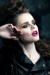 Fototapeta na wymiar Beautiful young woman with makeup smearing lipstick