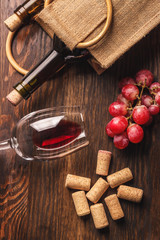 Glass with wine, bottle and bunch of grapes, wooden background